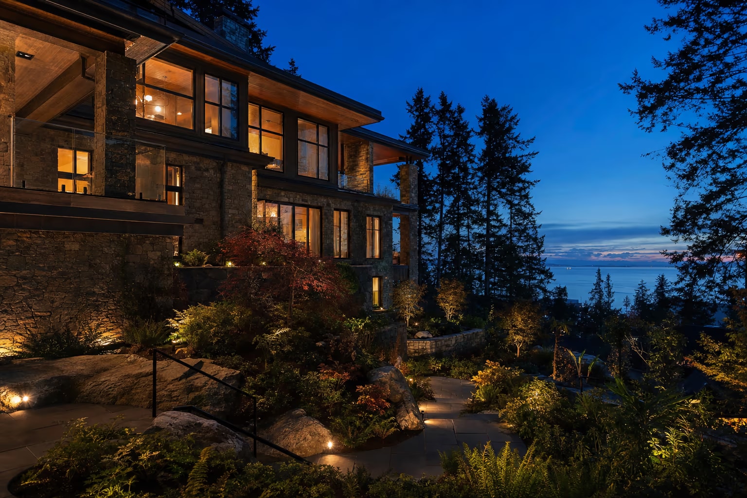 West Vancouver hillside home at blue hour with warm glowing windows and terraced garden