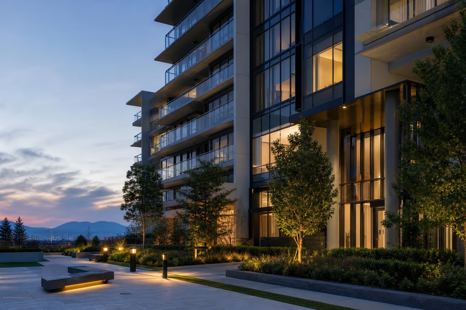 Modern Richmond condominium building at twilight with landscaped grounds and warm interior lights