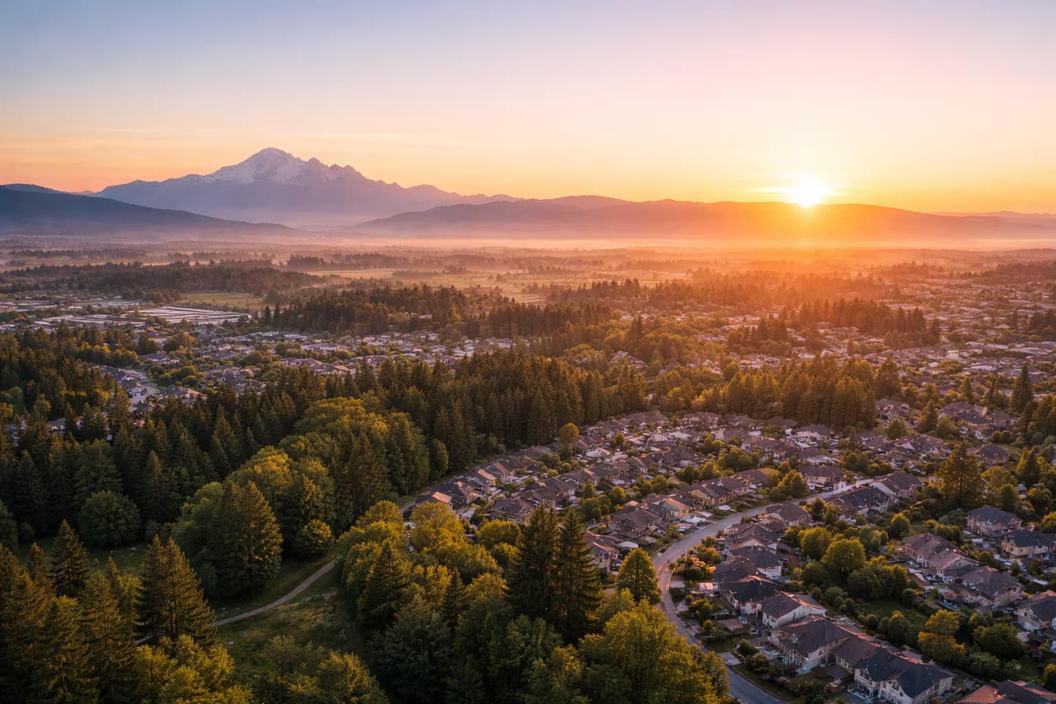 Sunrise aerial over Langley neighbourhoods with mountain backdrop